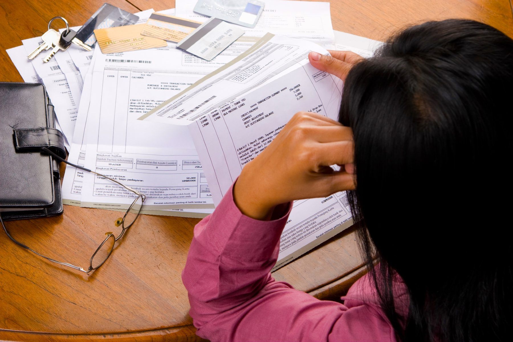 Woman sitting at table with bills spread out in front of her