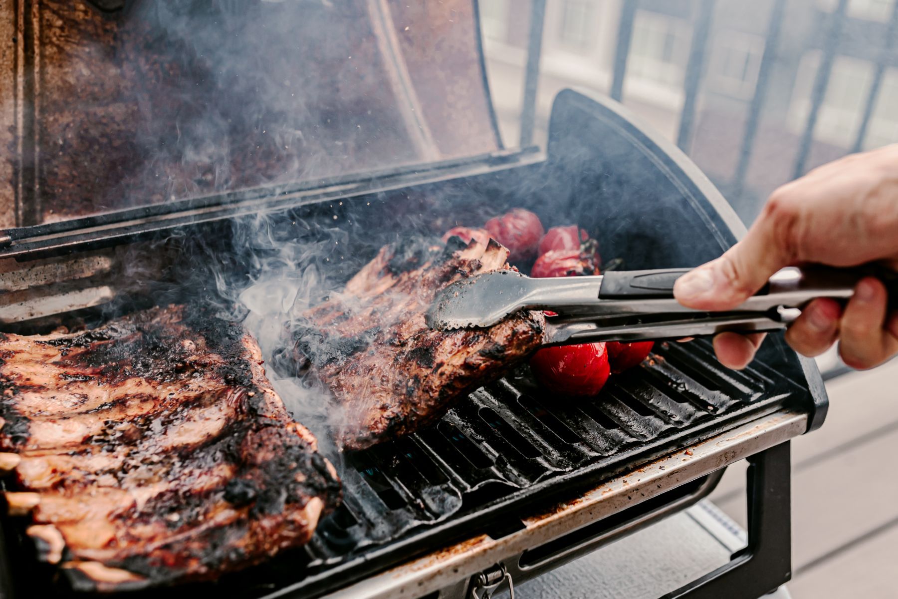 Man grilling ribs and vegetables on balcony