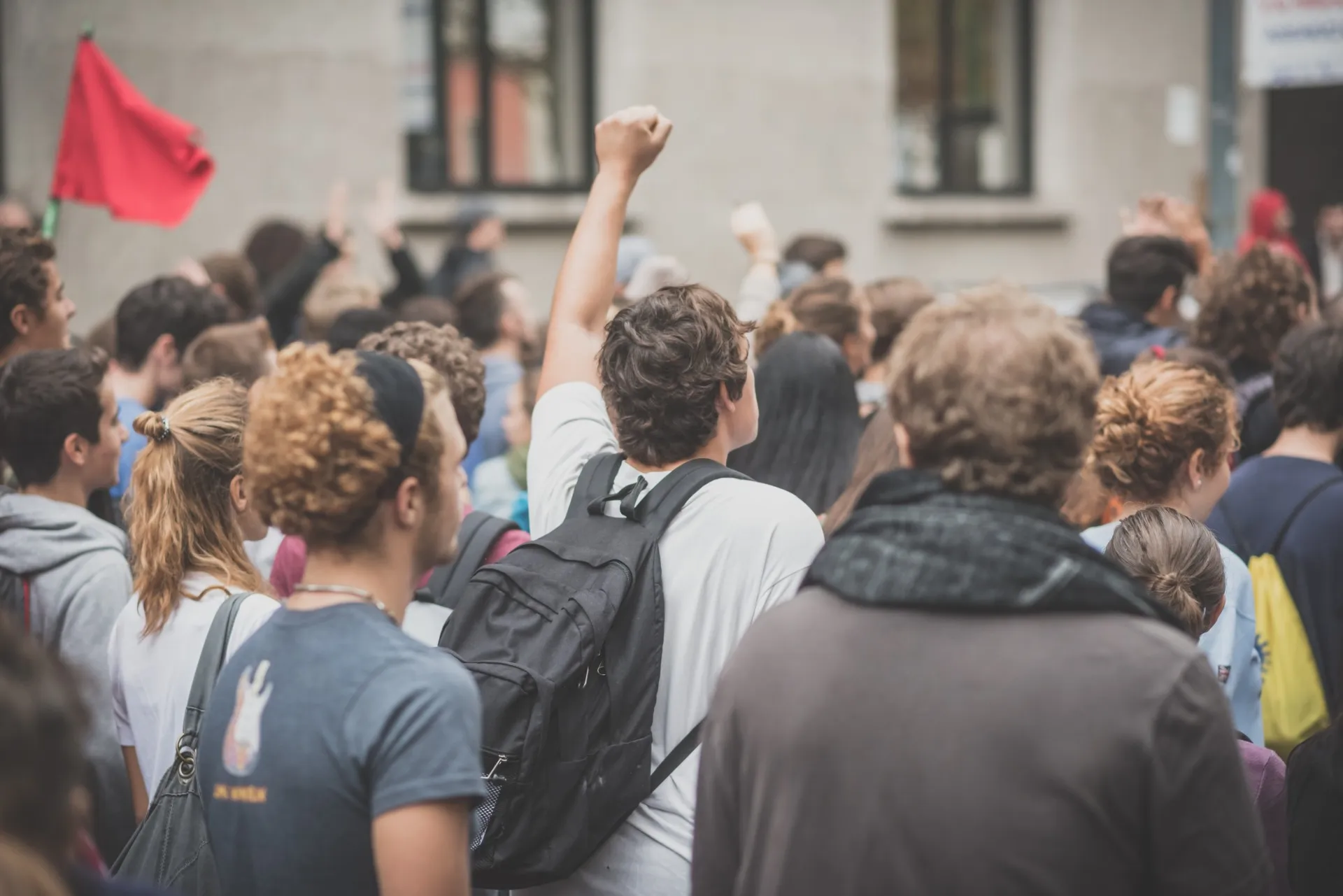 Man wearing backpack raises fist among crowd during protest - protesters' rights
