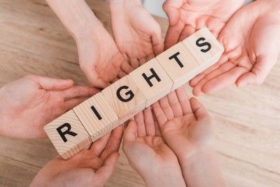 Eight hands hold wood letter blocks that read "rights" - Protesters' rights