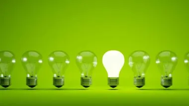 One in a row of lightbulbs is lit up against a green background - Bulb