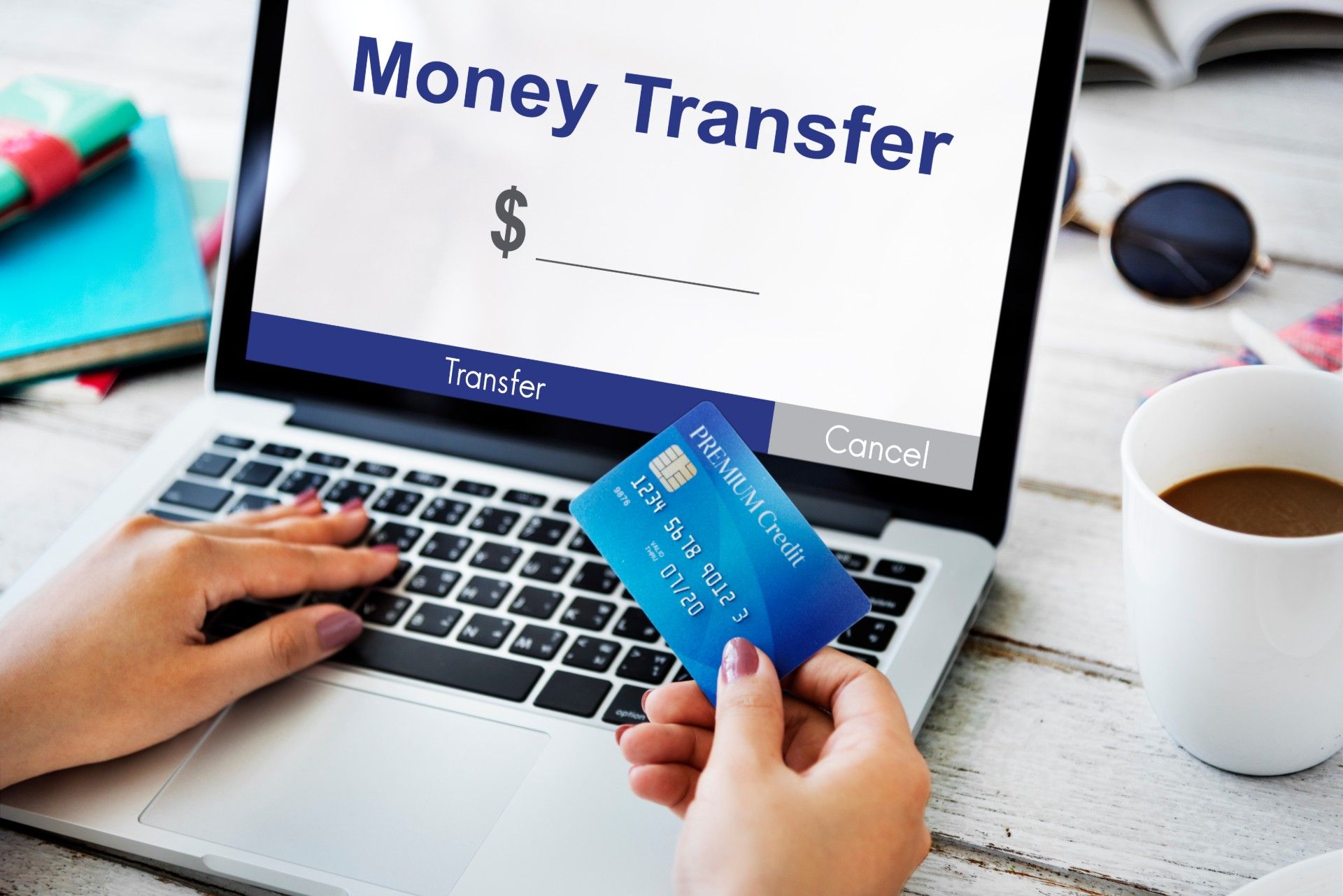Woman holding credit card uses a laptop to transfer money - scam victims
