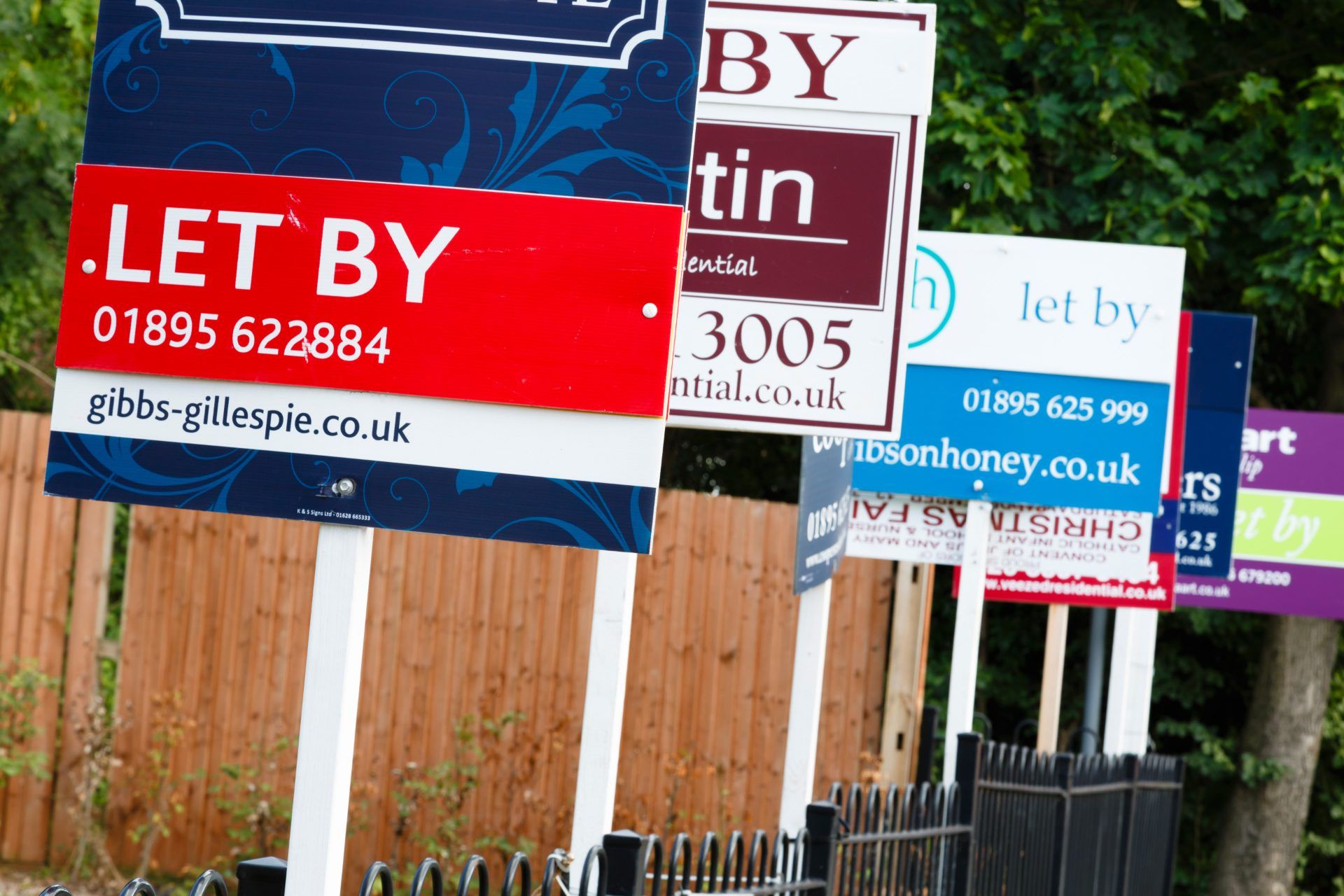 A row of "to let" signs outside a wood fence - no dss