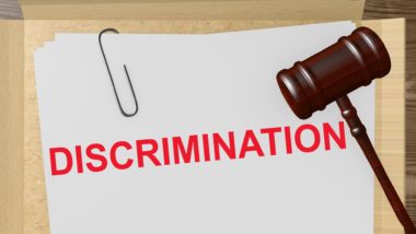 Filed folder with paperclipped paper that reads "discrimination" in red, with gavel - Garrick Club