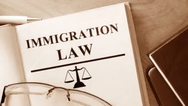 An immigration law book sits open with glasses lying on top - deportation to uganda