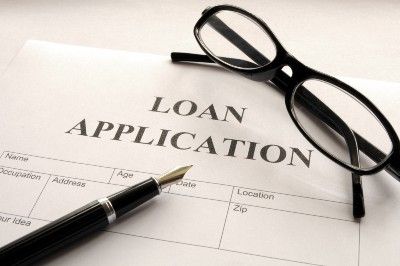A pen and pair of glasses sit on top of a blank loan application - double-glazing firms