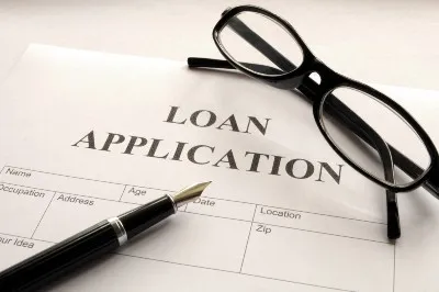 A pen and pair of glasses sit on top of a blank loan application - double-glazing firms