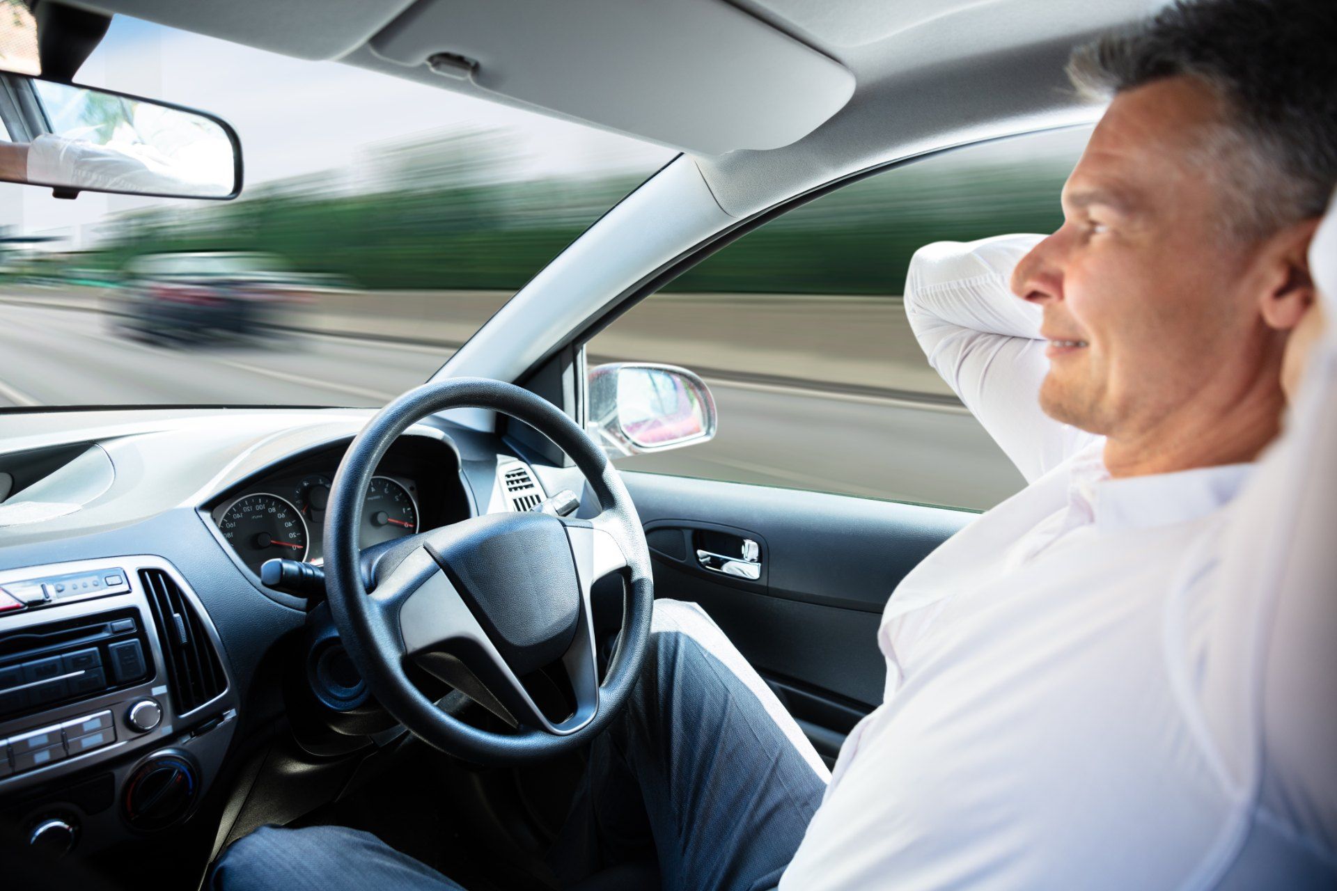 A man sits in the driver seat of a self-driving car - self-driving cars