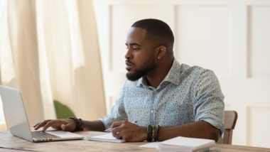 A man studies at home using a laptop and notebooks at a table - tuition fee refunds