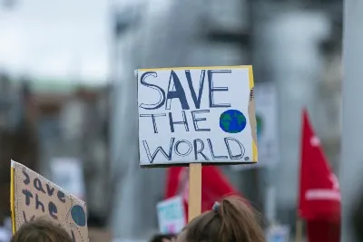 Person holds up a "save the world" sign at a protest - Portuguese children