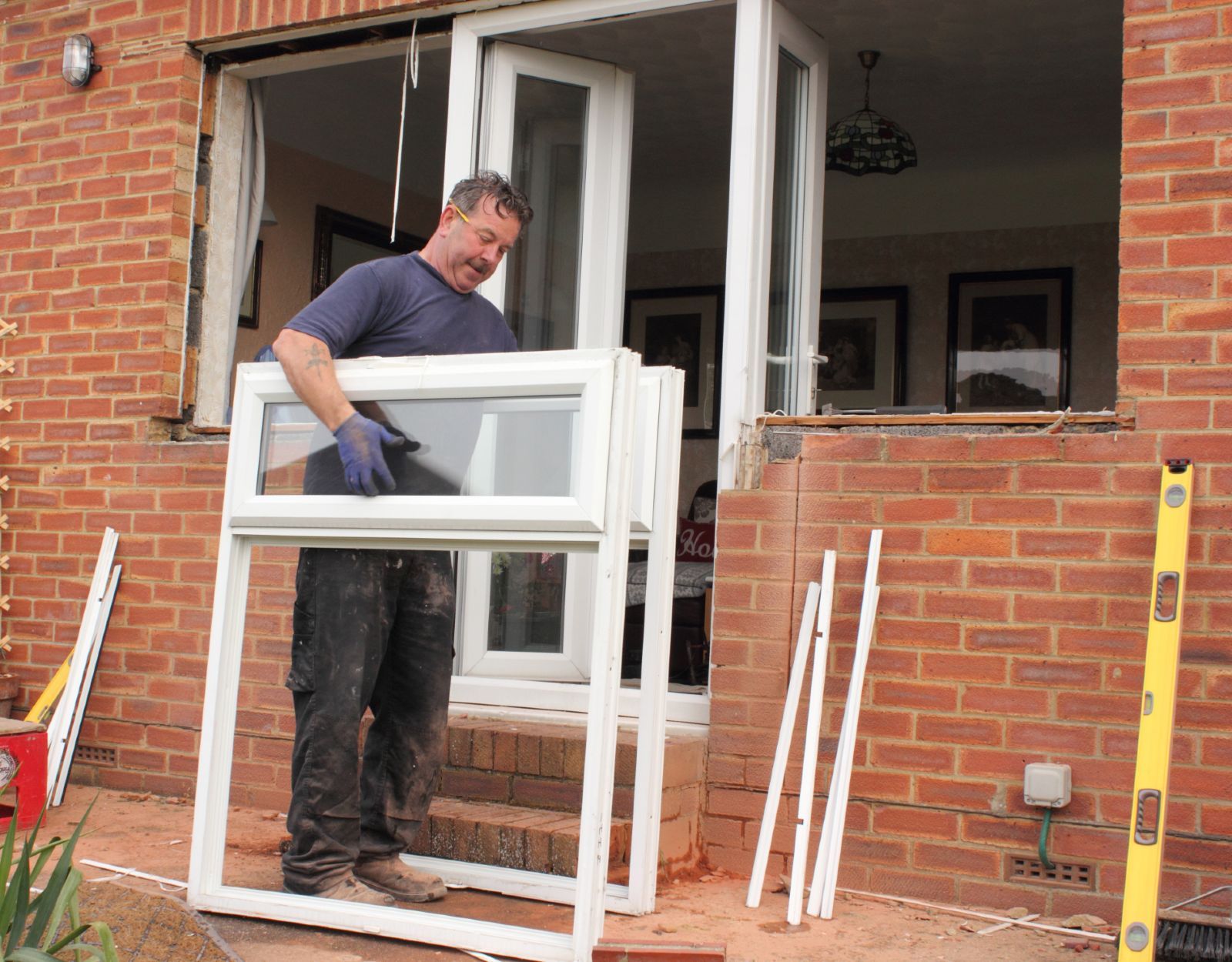 A man installs new windows on a brick house - double-glazing firms