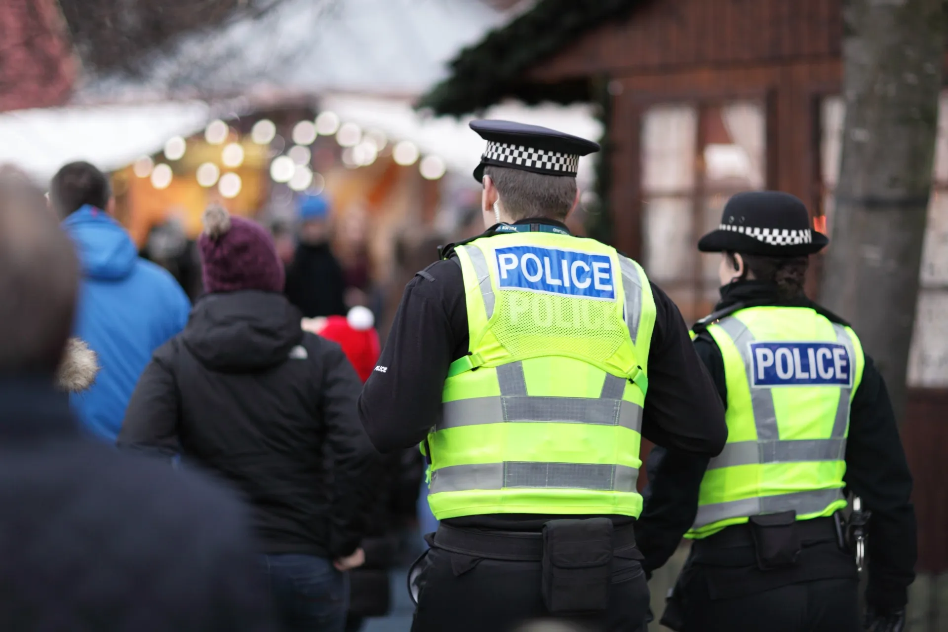 Two British police officers are seen from behind wearing reflective yellow vests that say "police" - police federation cyberattack