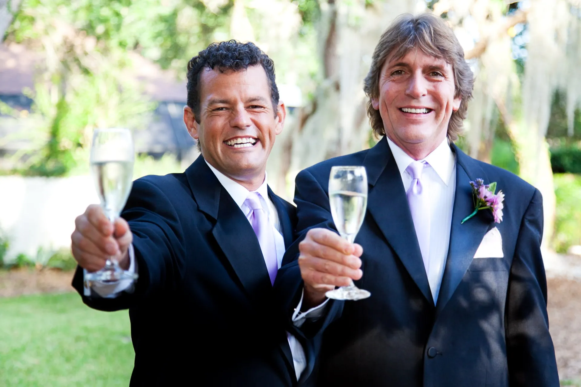 A male same-sex couple toasts with champagne at their wedding - civil partnerships