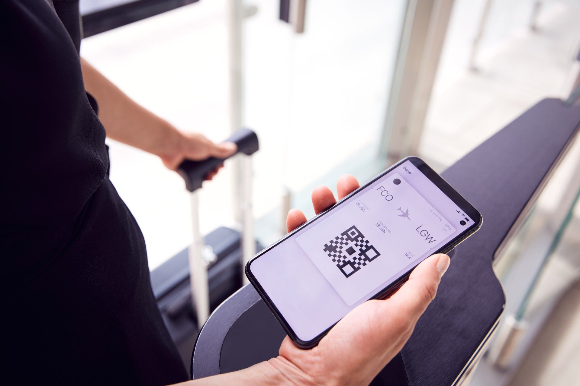 A man holds a phone displaying a mobile boarding pass at an airport - covid passport