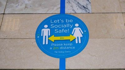 Stickers on the ground remind people to maintain social distancing - england lockdown