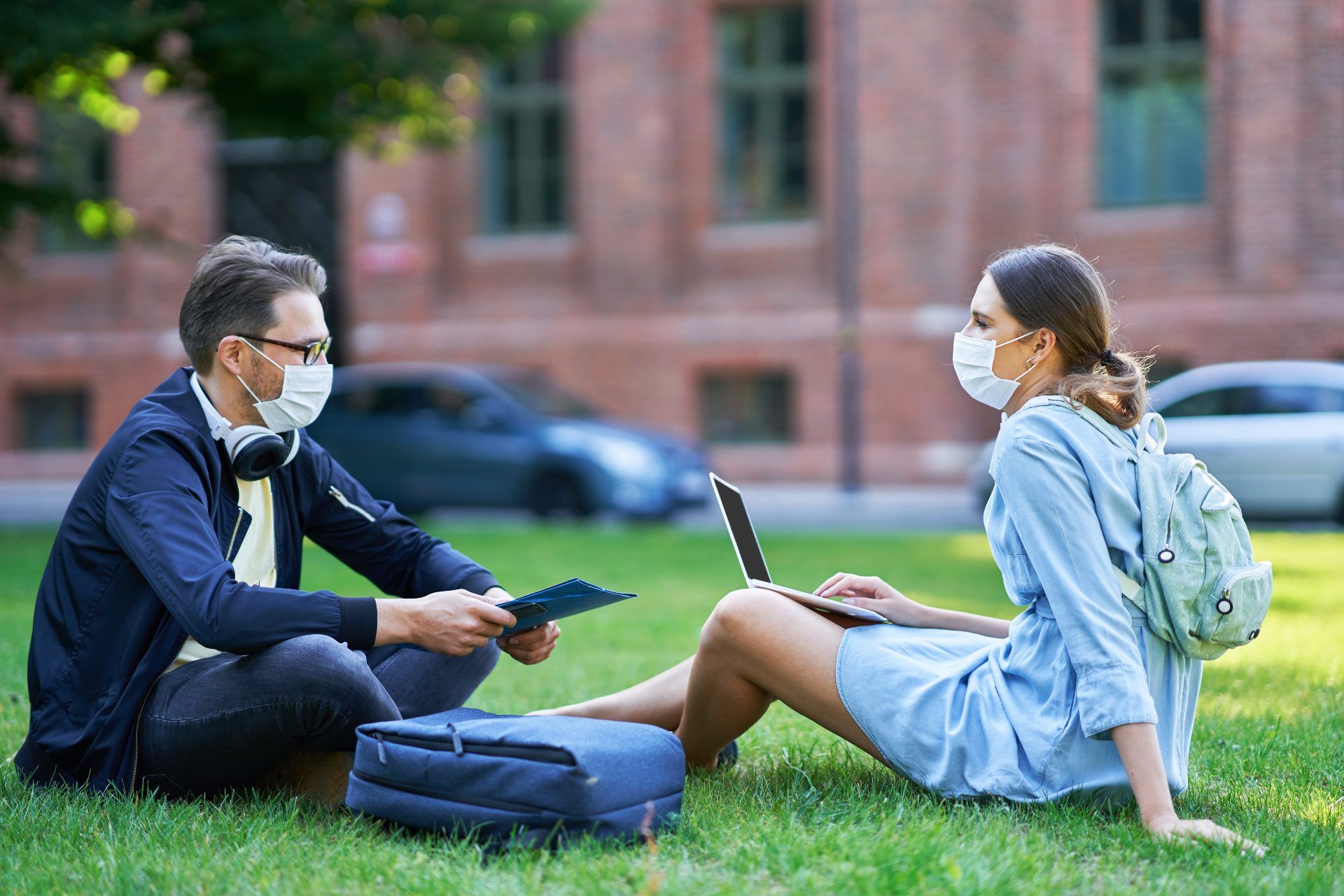 Two students wearing masks sit on the lawn at university - u.k. universities reopening