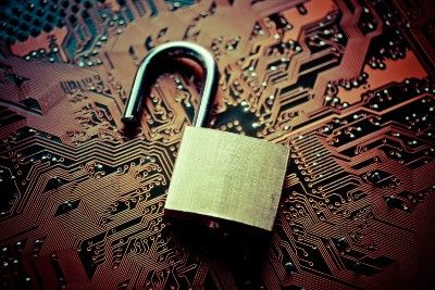 An open brass padlock lies on top of a copper circuit board - 118 118 money