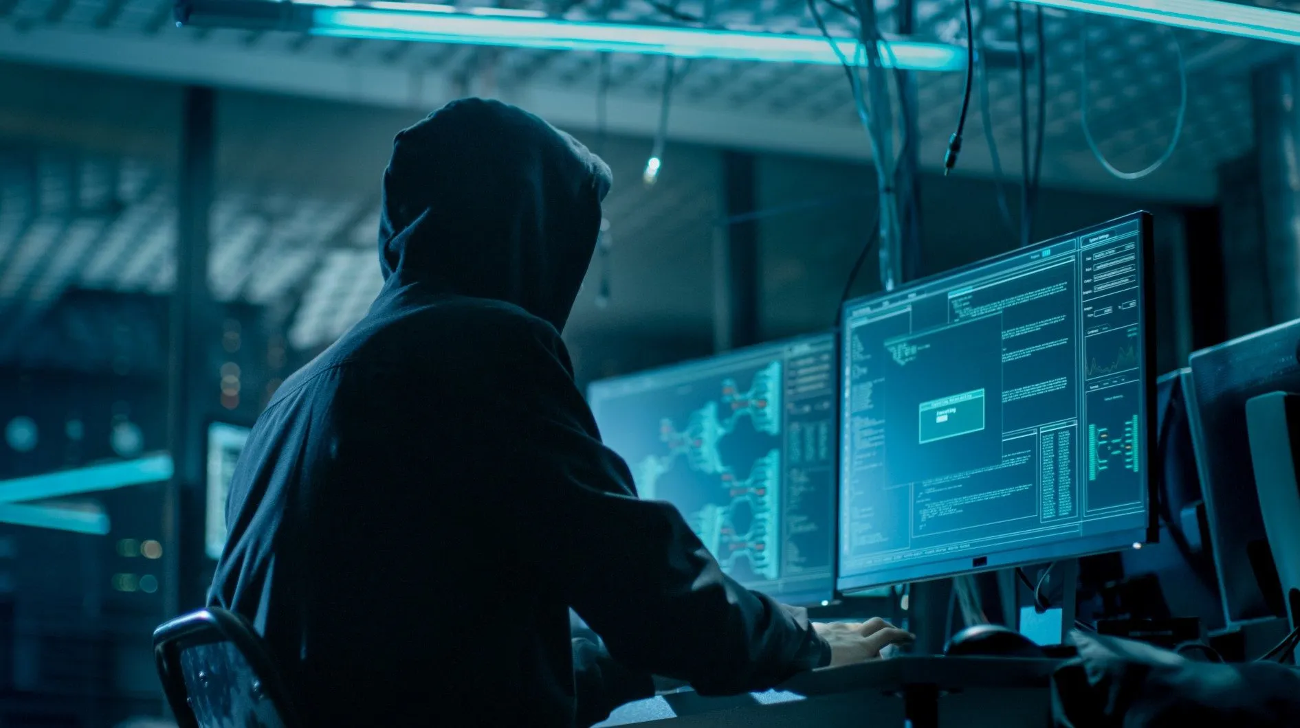 A hacker in a hoodie sits looking at a computer monitor - transform hospital group