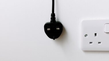A black plug from the United Kingdom is hanging on white background. energy crisis concept.