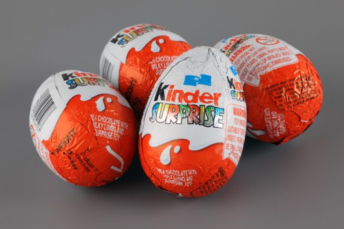 Four Kinder Surprise Eggs on grey background.