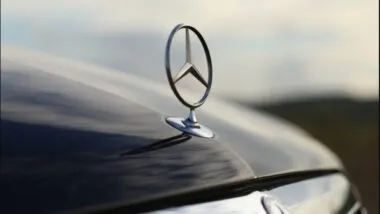 Close up of Mercedes emblem against a cloudy sky.