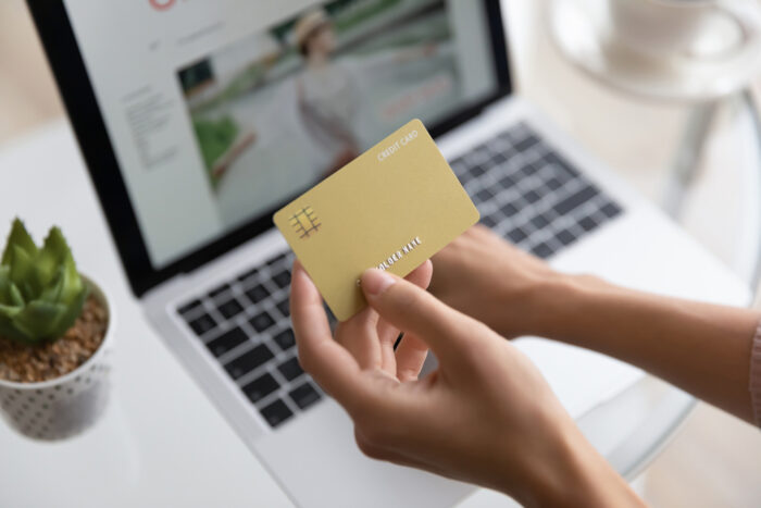 Close up of hands holding credit card with laptop computer in the background. Online shopping concept.
