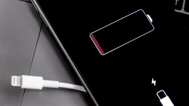 Apple iPhone smartphone with Lightning cable and battery logo on the display.