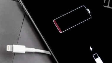 Apple iPhone smartphone with Lightning cable and battery logo on the display.