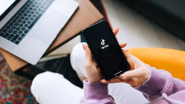 woman holding iPhone with TikTok app logo on the screen.