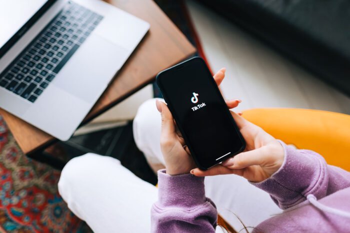 woman holding iPhone with TikTok app logo on the screen.