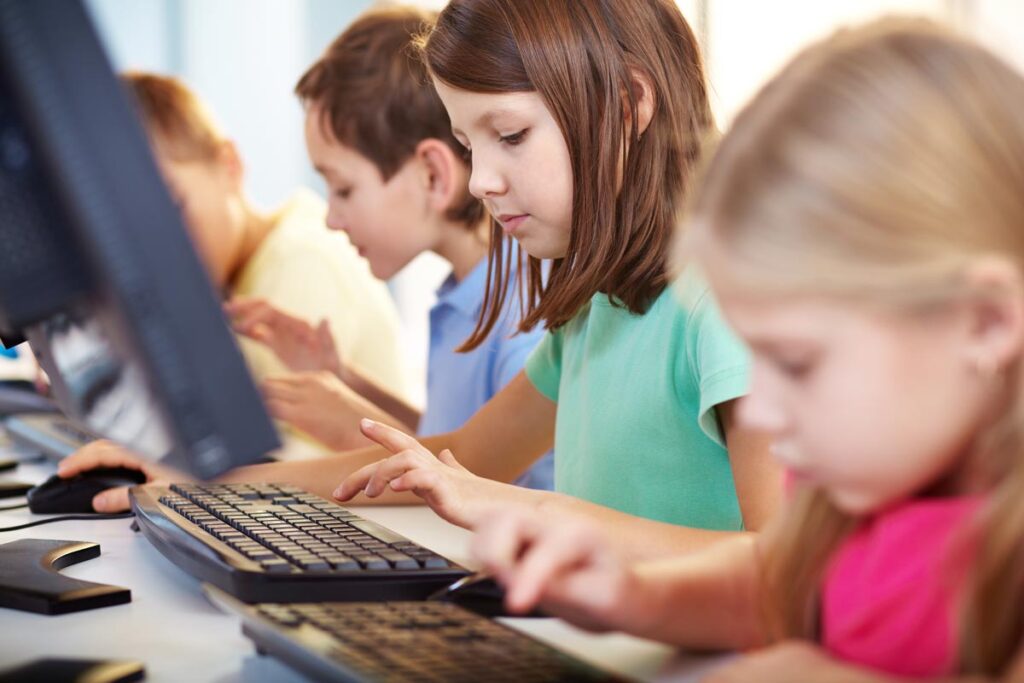 Portrait of a schoolgirl looking at computer keyboard while typing