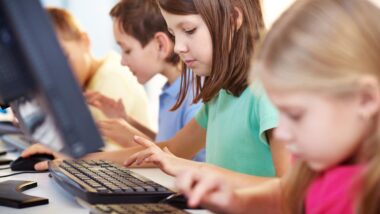 Portrait of a schoolgirl looking at computer keyboard while typing