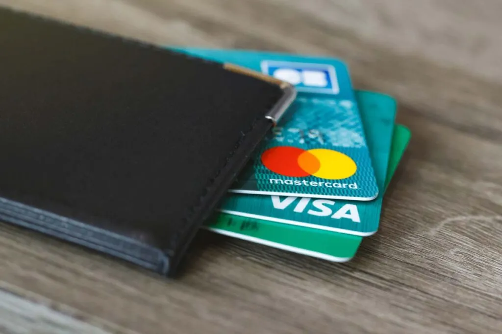 Mastercard and Visa cards peaking out of a wallet, representing the Mastercard and Visa fees cap.